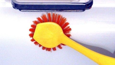 Eine gelbe Bürste wird auf einer weißen Badewanne verwendet, um sie gründlich zu reinigen und dafür zu sorgen, dass sie strahlt.