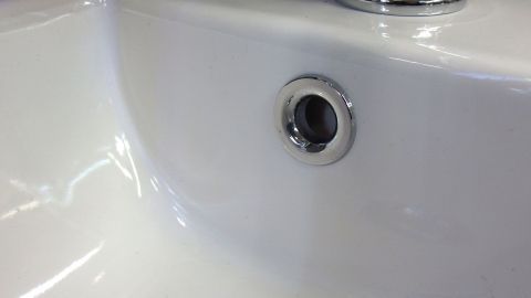 Ein glänzendes Waschbecken mit einem Abfluss sichtbar. Der Abfluss sieht sauber aus und ist bereit für die Nutzung, mit Hygiene im Hinterkopf.