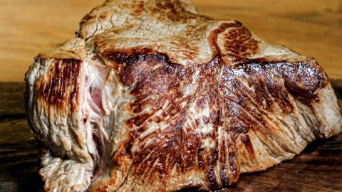 Saftiges, schön braunes Bratenstück liegt auf einem Holzbrett, bereit für die Zubereitung einer köstlichen Sauce.