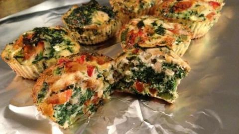 Bunte Eiklar Muffins liegen appetitlich auf Folie, mit frischem Gemüse und Kräutern, ideal für einen gesunden Snack.
