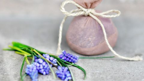 Ein nachhaltig verpackter Beutel liegt neben einem frischen Strauß lila Blumen, der für ein kreatives Recycling steht.