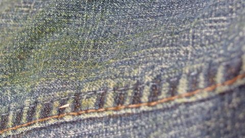 Jeans mit Grasflecken auf der Oberfläche; Nahaufnahme zeigt eine grüne Verfärbung auf dem blauen Stoff.