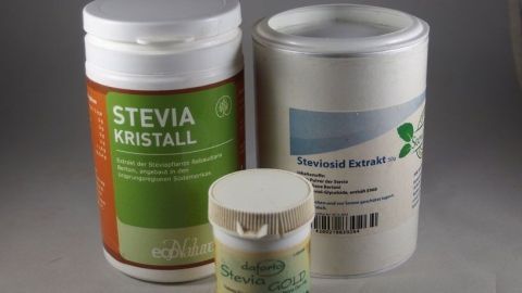 Drei Verpackungen mit Stevia in verschiedenen Größen stehen nebeneinander auf einem neutralen Hintergrund und vermitteln eine süße Alternative für Tee.