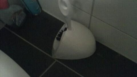 Ein Klobürstenhalter steht auf dem Badezimmerboden. Die Bürste ist in der Halterung und bereit zur Benutzung.