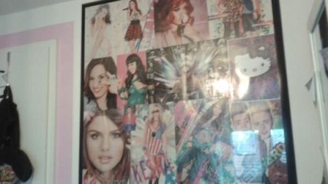 Ein großformatiger Bilderrahmen zeigt ein Collage-Poster mit verschiedenen Porträts und Models an einer Wand im Zimmer.
