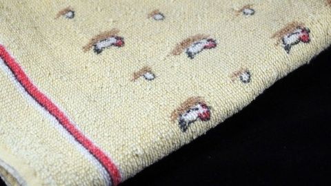 Ein altes Frotteehandtuch mit bunten Mustern liegt auf einem dunklen Untergrund, bereit zum Gebrauch als Lappen.