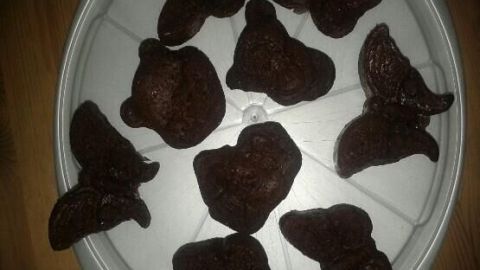 Schokoladenkuchen in Tierformen liegen auf einem weißen Tablett, präsentiert auf einem Holztisch.