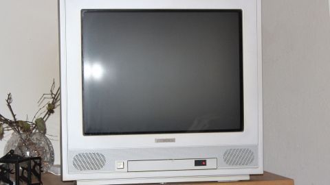 Ein veralteter, verrauchter Fernseher steht auf einem Regal, bereit zur Reinigung mit Backofenspray.