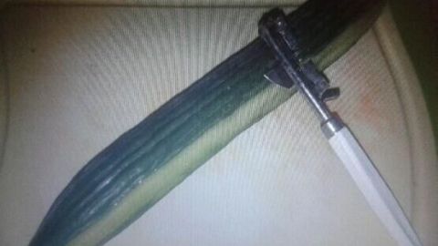 Eine Gurke liegt auf einem Holzbrett, während ein Schäler bereit ist, um sie zu schälen und Bitterstoffe zu entfernen.