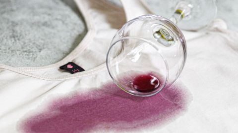 Ein Weinglas liegt umgekippt auf einem T-Shirt, während rote Flecken vom Kirschlikör darauf verteilt sind.