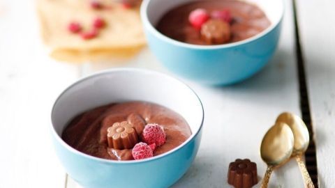 Zwei Schalen mit Schokopudding stehen auf einem Tisch, dekoriert mit Himbeeren und einem kleinen Schokoladenstück.