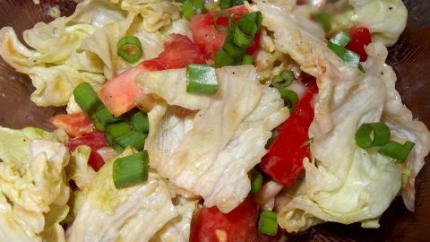 Frischer Salat mit buntem Gemüse, garniert mit Kürbiskernöl, liegt in einer Schüssel auf einem Holzuntergrund.