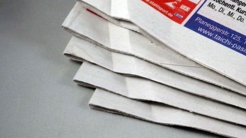 Gestapelte Tageszeitungen liegen ordentlich auf einem Tisch und warten darauf, gelesen oder weiterverwendet zu werden.