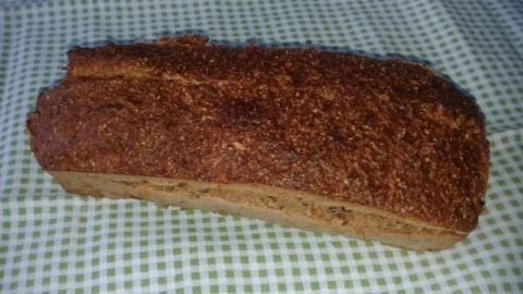 Ein Laib Eiweißbrot liegt gebacken auf einem grün-weiß karierten Tuch, seine Kruste ist goldbraun und knusprig.