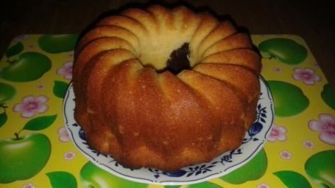 Ein saftiger Rührteigkuchen steht auf einem bunten Untersetzer und wirkt einladend auf einem Holztisch.