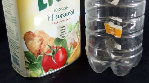 Aufkleber und Preisschilder mithilfe von Speiseöl entfernen. Ein Behälter mit Aufkleber steht neben einer Plastikflasche, die ebenfalls ein Preisschild trägt.