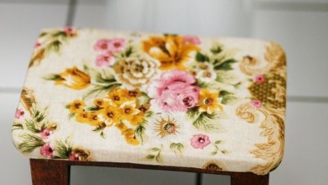 Ein kleiner Hocker mit einem floralen Muster steht neben einer Toilette, um die Darmgesundheit zu unterstützen.