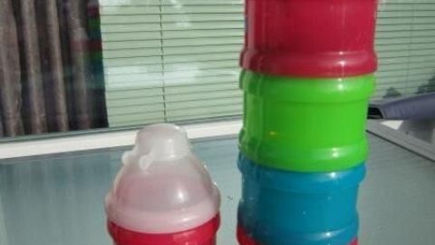 Bunte, stapelbare Gewürzbehälter stehen auf einem Tisch, sortiert nach Farben, im Hintergrund helle Fensterscheiben.