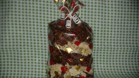Eine Tüte mit verschiedenen Weihnachts-Crossies steht dekorativ auf einem grünen karierten Hintergrund, reich verpackt.