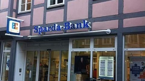 Die Sparda-Bank-Filiale steht in einer traditionellen altstadtartigen Umgebung, mit einem Fahrrad vor der Tür.