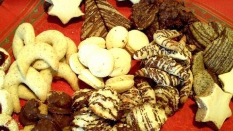 Zimtsterne und andere Plätzchen liegen schön auf einem roten Teller, bereit, genossen zu werden.