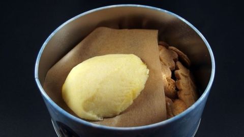 Kekse liegen in einer Dose, während ein Stück Butter darauf liegt, um die Plätzchen weich zu halten.