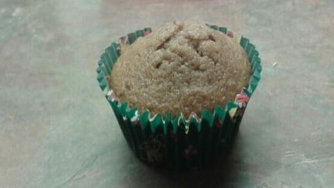 Ein Lebkuchen-Muffin steht auf einer Küchenarbeitsfläche, umgeben von einem grünen Papierförmchen.