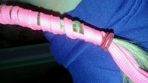 Ein haarförmiges Objekt ist mit elastischen, pinken Bändern umwickelt, um es ohne Hitze zu glätten.