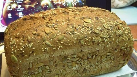 Ein Bio-Dinkelvollkornbrot liegt auf einer Unterlage, umgeben von einer unscharfen, gemütlichen Küche.