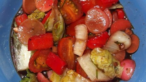 Bunte Salatzutaten liegen in einer blauen Schüssel und warten darauf, mit einer Salatsoße vermengt zu werden.