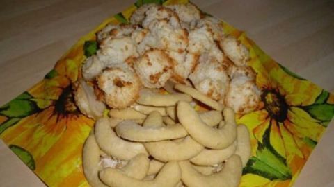 Auf einer bunten Serviette liegen frisch gebackene Vanillekipferl und Kokosmakronen, bereit zum Genießen.