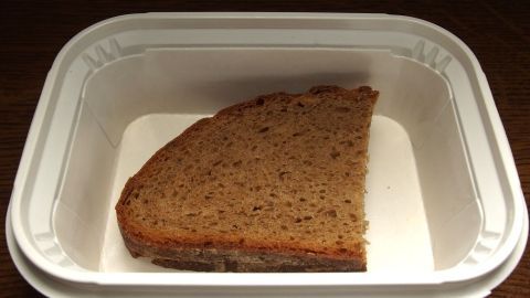 Eine kostenlose Brotdose enthält ein Stück Vollkornbrot, das allein auf einem weißen Untergrund liegt.