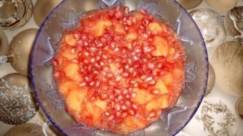 Ein bunter Granatapfel-Quittengelee in einer klaren Schüssel, präsentiert auf einem festlich dekorierten Tisch.