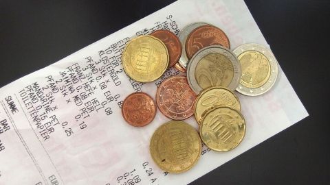 Eine Vielzahl von Münzen liegt auf einem Beleg, während Kinder spielerisch mit Geld rechnen und lernen.