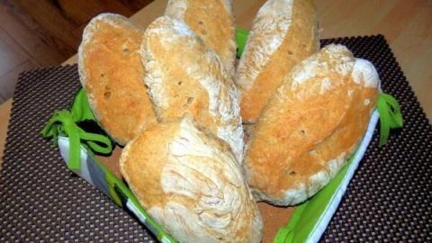 Dinkelbrötchen sind in einem Korb angeordnet und wirken frisch gebacken, auf einem rustikalen Tisch serviert.