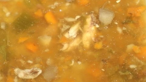 Eine goldene Soße mit Gemüse und kleinen Stückchen, die bereit ist, Weihnachtsgeflügel zu verfeinern.