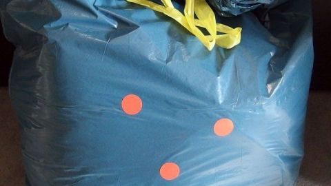 Ein blauer Sack mit gelbem Verschluss steht auf einer Oberfläche und zeigt orangefarbene Punkte, bereit für große Geschenke.
