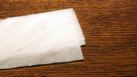 Ein Babypflegeöltuch liegt auf einer Holzoberfläche und wird zum Reinigen des Holzes verwendet.