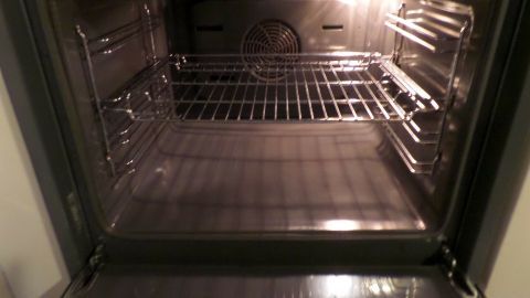 Ein Backofen steht offen, glänzend und sauber, mit einem Gitterrost im inneren, bereit zum mühelosen Reinigen.