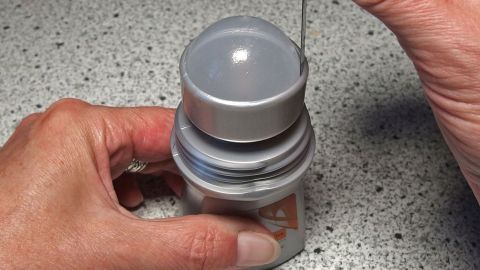 Eine Hand hält einen Deoroller, während sie den oberen Teil abnimmt, um den restlichen Inhalt zu verwenden.