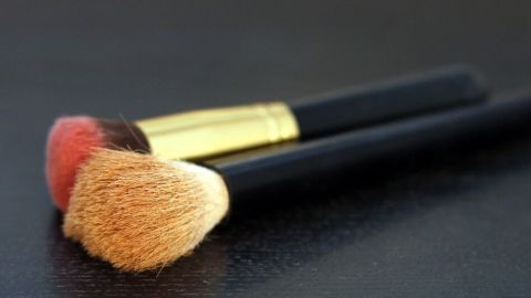Zwei preisgünstige Kosmetikpinsel liegen auf einer schwarzen Oberfläche, bereit für das Schminken oder Konturieren.