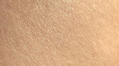 Glänzende, trockene Haut zeigt fein strukturierte Texturen diagonal im warmen Licht. Sie vermittelt ein Gefühl von Wellness.