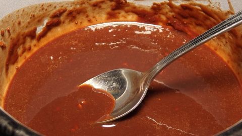 Eine cremige Schoko-Creme wird mit einem Löffel in einer Schüssel serviert, umgeben von einem schokoladigen Rand.