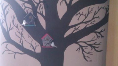 Baum ist auf die Wand gemalt, zwei Vogelhäuschen sind an den Ästen befestigt; der Schrank steht daneben.