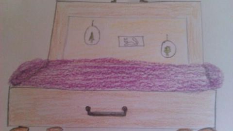 Ein Holzkoffer dient als Bett, ausgelegt mit einer lila Decke; an der Rückseite hängen Bilderrahmen mit Bäumen und einem Vogel.
