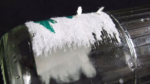 Eine Flasche mit einem Reinigungsmittel zeigt, wie Klebereste entfernt werden. Die weiße Substanz ist auf dem Behälter sichtbar.