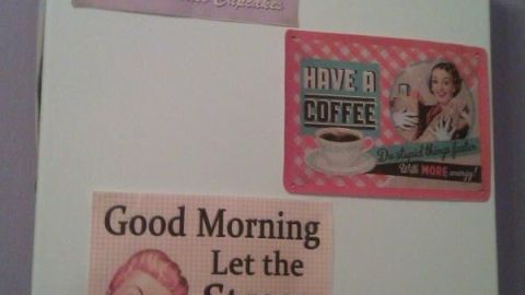 Gastherme verziert mit Retro-Postern: "Freshly Baked", "Have a Coffee", "Good Morning, Let the Stress Begin...", vor lila Wand.