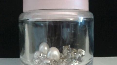 Eine durchsichtige Glasdose mit einem pinken Deckel, die Ohrringe und Schmuck sicher aufbewahrt.