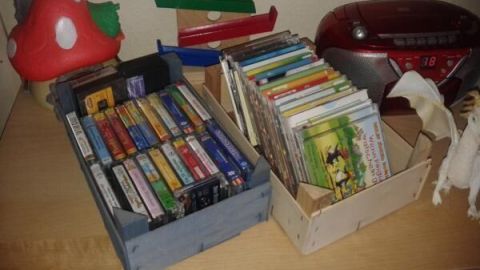 Kisten halten Kassetten und CDs auf einem Regal neben einem Radio und Spielzeugpilz, zeigen kreative Weiterverwendung.