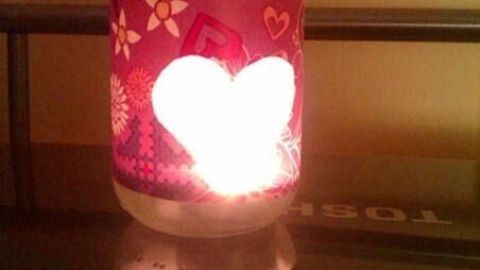 Ein Konservenglas mit herzförmigem Ausschnitt leuchtet warm in einem abgedunkelten Raum.
